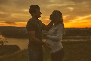 Husband  stroking his pregnant wife while  enjoy spending time together outdoor.Toned image. photo