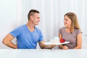 Young man is giving breakfast to his happy wife. photo