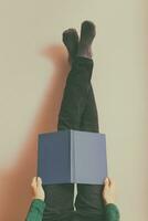 Woman resting and reading book with legs up in front of the wall.Toned photo. photo