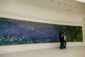 two people in front of a painting of water lilies photo