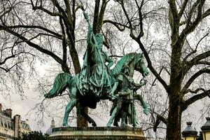 a statue of a man on a horse in front of a building photo