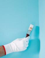 imagen de hombre participación Cepillo de pintura en frente de azul pared. foto