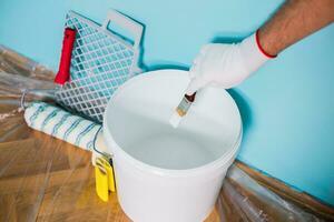 Image of man holding paint roller and equipment for painting wall. photo