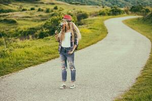 Beautiful young woman enjoys smelling bouquet of flowers at the country road.Toned image, photo