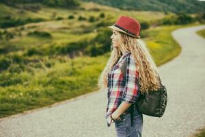 Beautiful young woman at the country road enjoys in the view.Toned image. photo