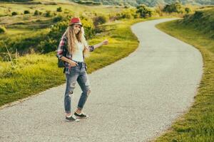 Beautiful young woman  hitchhiking at the country road.Toned image. photo