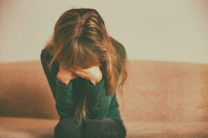 Depressed woman sitting alone at sofa.Toned image. photo