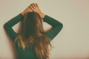 Depressed woman standing alone in front of wall.Toned image. photo