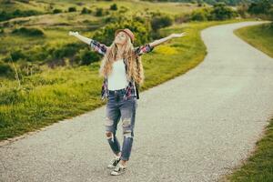 Beautiful young woman enjoys walking at the country road.Toned image. photo