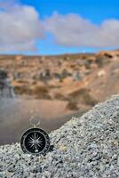a compass on a gravel cliff in the middle of a desert photo