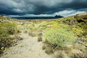 a dirt road in the middle of a desert with a stormy sky photo