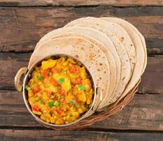 Indian Cuisine Spicy Fried Aloo Served with Indian Bread on Wooden Table photo