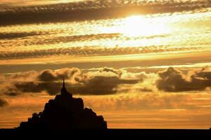 the sun sets behind the silhouette of a ruin photo