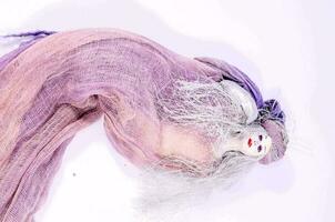 a purple cloth doll laying on a white surface photo