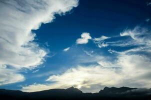 a blue sky with clouds and mountains in the background photo