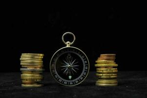 a compass and coins on a black background photo