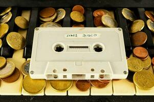 a cassette and coins on a piano keyboard photo