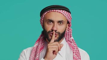 On camera, arabic person makes quiet signal with finger over lips, displaying silent mute gesture. In studio, private person does secretive confidentiality sign in an effort keep secret. video