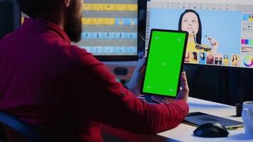 foto editor aan het leren van zelfstudie Aan groen scherm tablet terwijl werken in onafhankelijk productie bedrijf. fotograaf aan het kijken online gids Aan mockup apparaat over aanpassen wit balans video