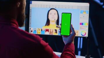 Photographer following online tutorial on mockup phone about using photo editing software to improve images quality. Photo editor learning from online guide on green screen smartphone video