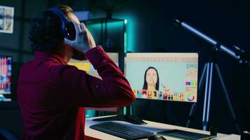 fotógrafo dentro criativo estúdio trabalhando em digital portfólio exibindo sessão de fotos editado imagens. foto editor selecionando melhor fotografias enquanto ouvindo música dentro fones de ouvido video