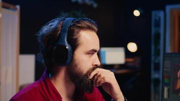 video producent lägger till ljud effekter till filma montage, arbetssätt i studio, stänga upp panorering skott. videographer använder sig av hörlurar till testa och förbättra audio kvalitet använder sig av specialiserade programvara på dator