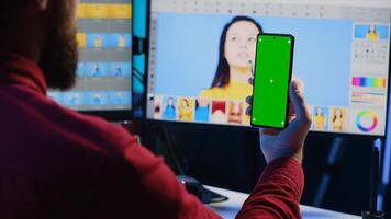 Photographer following online tutorial on mockup phone about using photo editing software to improve images quality. Photo editor learning from online guide on green screen smartphone