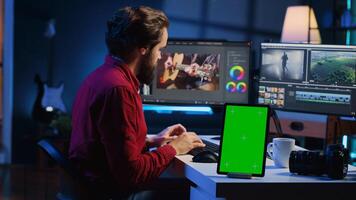 vídeo editor agrega sonido efectos a filmado imágenes, trabajando en enviar producción estudio con verde pantalla tableta. camarógrafo utilizando auriculares a prueba y mejorar audio calidad siguiente a Bosquejo dispositivo foto
