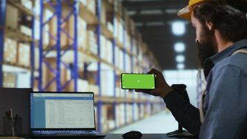 Storehouse advisor checks greenscreen on phone layout, working on package transport and logistics in industrial warehouse. Quality control manager uses isolated copyspace display. photo