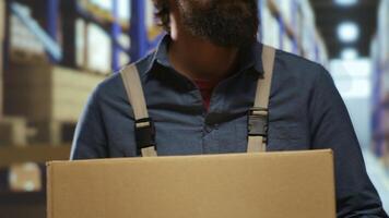 Packaging engineer carrying cargo boxes in depot, trying to organize stock and production based on parcel or label numbers. Storehouse worker preparing to put packages on industrial racks. photo