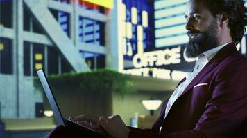 Successful investor works on laptop outside in the city center, using digital investment statistics online. Entrepreneur acting like a workaholic downtown, examining global revenue trends. photo