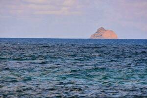 the ocean with a small island in the distance photo