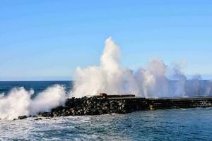 a large wave crashing into the rocks at the ocean photo