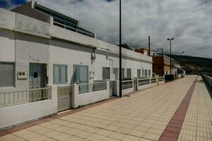 a walkway with white buildings and a cloudy sky photo