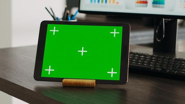 Greenscreen projection on interactive tablet with chromakey theme appears on company desk. Isolated mockup design displayed on advanced handheld gadget, blank copyspace layout. Close up. photo
