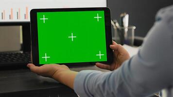 POV of manager holds smartphone with isolated greenscreen layout, working with blank mockup chromakey template at office desk. Young man looking at mobile device display with copyspace. photo