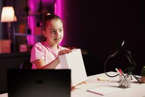 Gen Z content creator filming herself unboxing product popular among children watching her online social media content. Happy little media star recording video unpacking item photo