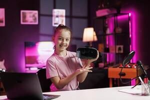 Smiling kid filming sponsored content, unboxing newly released VR glasses product to make fans buy it. Child entertainer amazed by product, presenting impressive virtual reality headset to subscribers photo