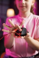 Close up shot of young girl in studio reviewing gaming mouse in front of camera in personal studio. Cheerful kid filming electronics haul, testing scrolling wheel on wired computer peripheral photo