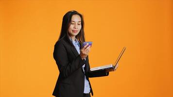 Stylish person ordering clothes online on modern pc, using debit card to make electronic transaction in studio. Young woman typing banking credentials on website for shopping session. photo