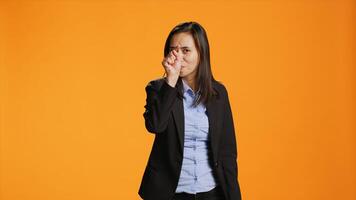 asiático oficina empleado señalando dedos a cámara, siendo grave y confidente terminado naranja antecedentes. mujer en formal ropa indica alguna cosa en frente de su, punto a el lente. foto