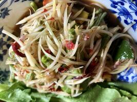 Thai papaya salad or Somtum on table. close up view of delicious asian food photo