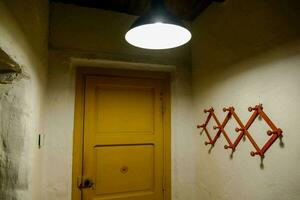 a hallway with a yellow door and a light fixture photo