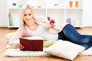 mujer comiendo manzana y leyendo libro a su hogar foto