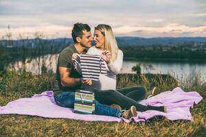 Happy couple enjoy looking at their with baby clothing and relaxing outdoor. photo
