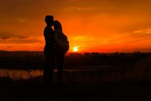siluetas de marido y embarazada esposa disfrutar gasto hora juntos al aire libre imagen. foto