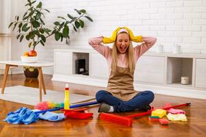 Image of  overworked housewife with cleaning equipment shouting while sitting in the living room. photo