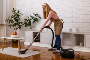 Beautiful housewife cleaning with vacuum cleaner her home. photo