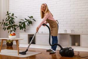 Beautiful housewife cleaning with vacuum cleaner her home. photo