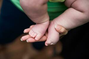 imagen de pequeño bebé piernas en madre manos. atención en bebé dedos. foto